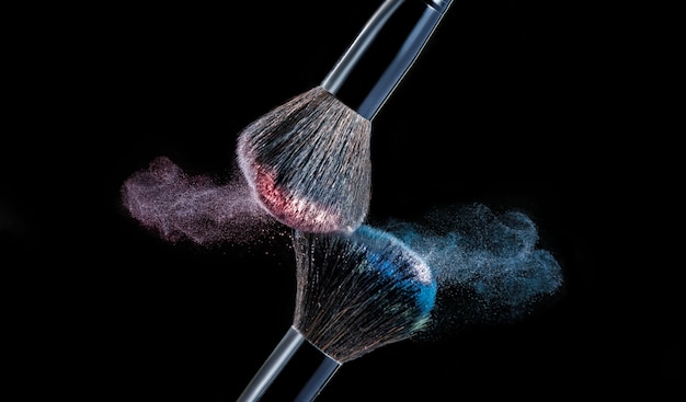 Photo make up brush with powder splashes on black background