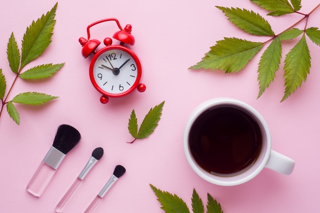 Make-up brushes, a Cup of coffee and clock. Beauty concept.