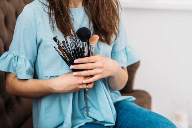 Trucco pennelli nelle mani di bella giovane donna alla moda