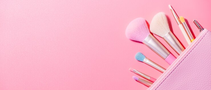 Make up brushes with powder on pink surface