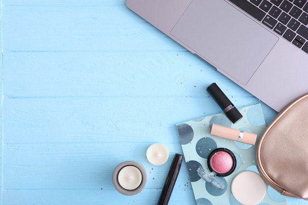 Make-up cosmetica en moderne laptop op een gekleurde achtergrond bovenaanzicht