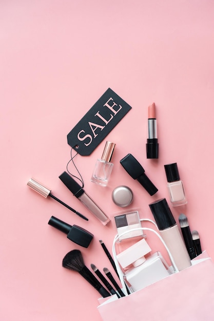 Make-up cosmetische parfum vrouwenproducten accessoire gieten uit boodschappentas op roze platte lay achtergrond, schoonheidsproducten goedkope korting detailhandelsaanbieding online aankoop, bovenaanzicht boven verticale kopie ruimte