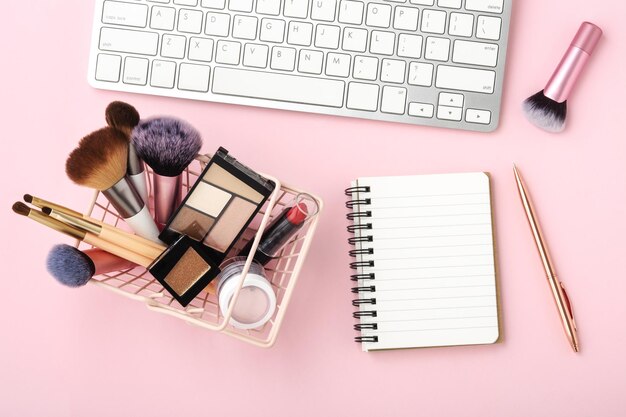 Make-up cosmetische producten met notebook en toetsenbord op pastelroze bureau