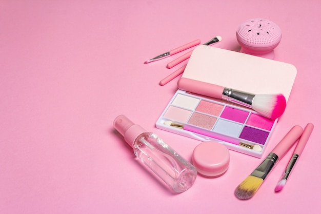 Make-up cosmetische set en haarkammen op roze.
