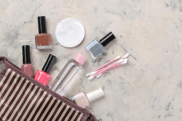 Make-up kit Damescosmetica in een make-uptas en make-upborstels op een lichte betonnen achtergrond, vrouwendingen bovenaanzicht