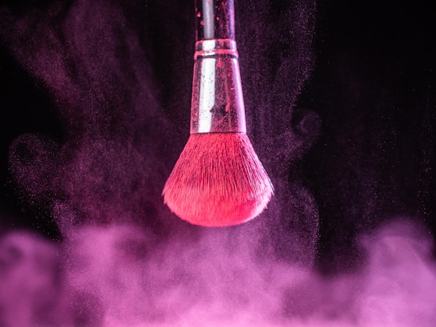 Make-up kwast met roze poeder spatten explosie op zwarte achtergrond Beauty concept