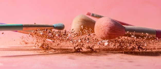 Make-up kwasten met poeder spatten geïsoleerd op roze