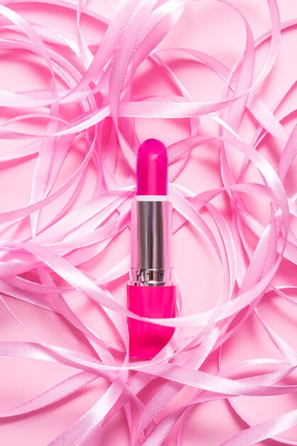 Make up Lipstick on pink table decorated with pink ribbon