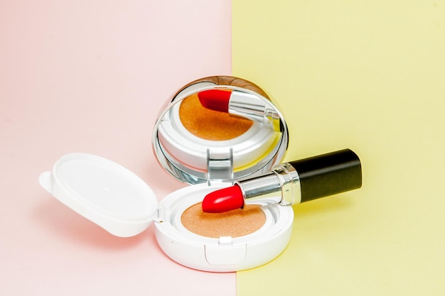 Make up products spilling on to a bright yellow and pink background with copy space