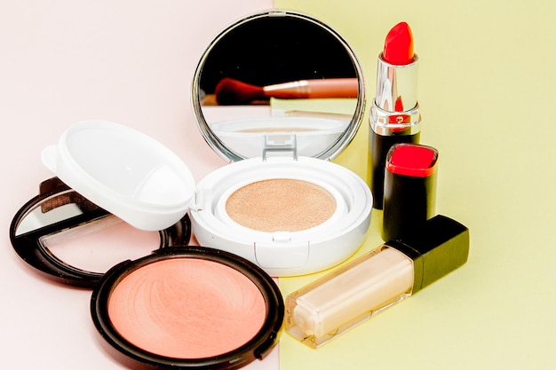 Make up products spilling on to a bright yellow and pink background with copy space