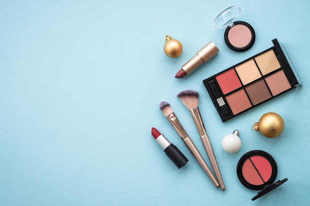 Make up products and winter decorations on blue background Winter cosmetic Flat lay image with copy space