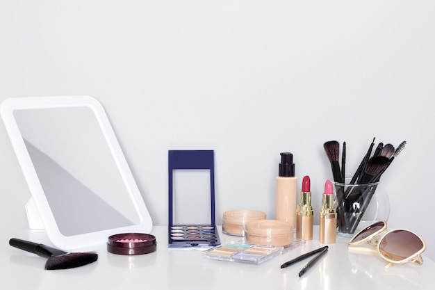 Make-up products with mirror on dressing table. Vanity table with makeup accessories