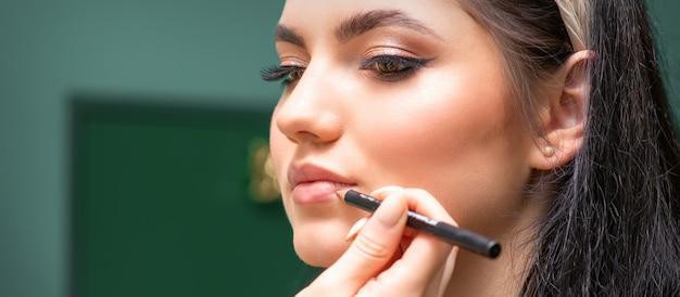 Make-up professionele artiest of schoonheidsspecialist schildert contourlippen van een jonge vrouw met een potlood close-up.