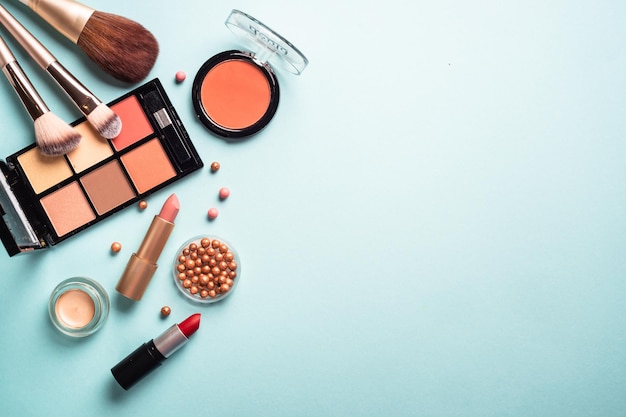 Make-up professionele cosmetica op blauwe achtergrond Poeder lippenstift schaduwborstels Plat gelegd met kopieerruimte