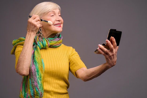 Make-up. Short-haired blonde senior woman doing make-ip