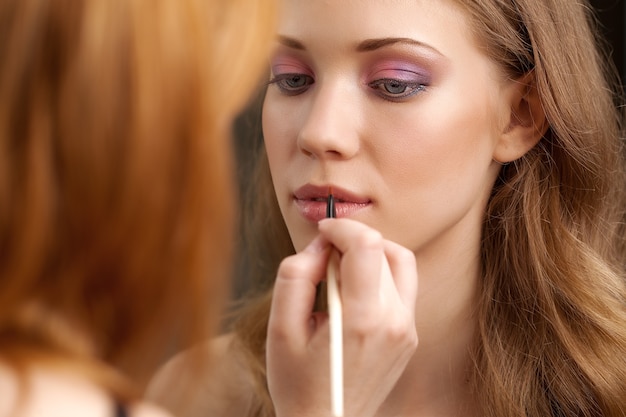 Make-up in studio, before a mirror, on a dark background