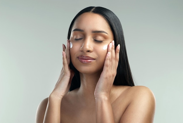 Make-up verbergt je gebreken dit product lost ze op Shot van een mooie jonge vrouw die vochtinbrengende crème op haar huid aanbrengt