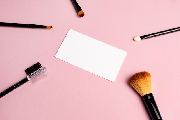Make-upborstel en wit visitekaartje op roze achtergrond Een horizontale sjabloon voor een visitekaartje van make-upartiest39s of flyerontwerp met kopieerruimte