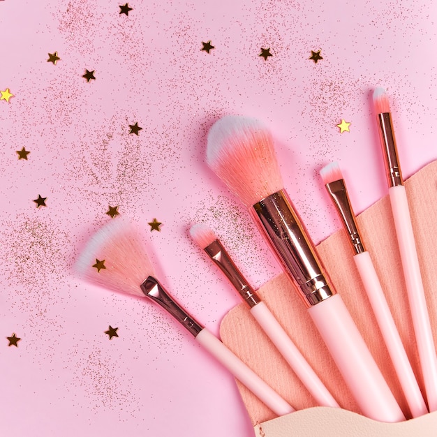 Make-upborstels in cosmetische tas en glanzende schittert op roze oppervlak
