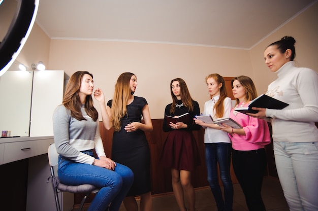 Make-upleraar met haar studentenmeisjes. Make-up tutorial les op schoonheidsschool. Make-up masterclass.