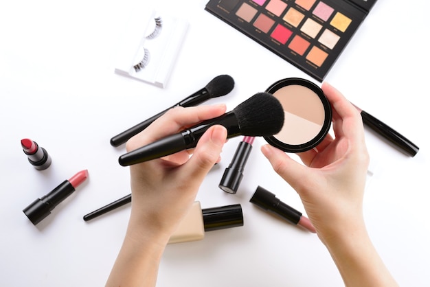 Make-uppoeder in handen van de vrouw Professionele make-upproducten met cosmetische schoonheidsproducten foundation lippenstift oogschaduw wimpers wimpers borstels en gereedschap