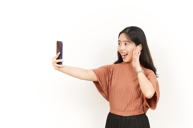 Сделать видеозвонок с помощью смартфона красивой азиатской женщины, изолированной на белом фоне