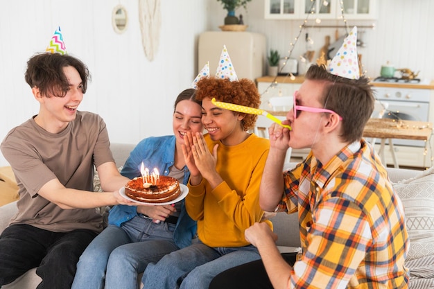 생일 케이크에 불타는 불을 불어넣는 파티 모자를 입은 여자