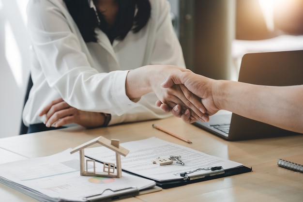 Makelaar en klant schudden elkaar de hand na het beëindigen van het contract na een woningverzekering en investeringslening.