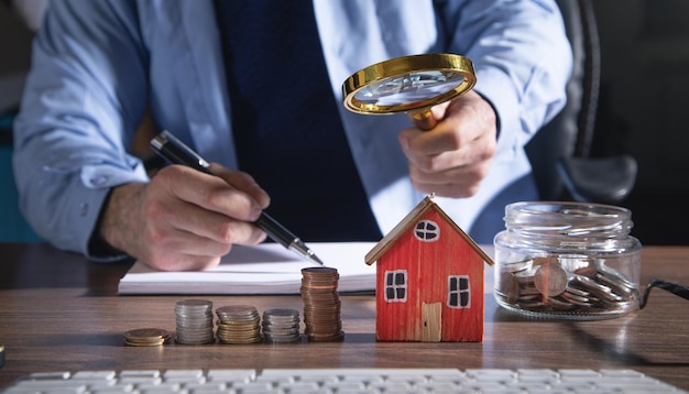 Makelaar in onroerend goed die vergrootglas op huismodel houden