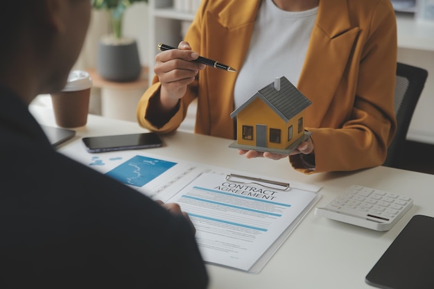 Makelaar in onroerend goed Lever een voorbeeld van een modelhuis aan de klant hypothecaire leningovereenkomst Maken van lease en kopen en verkopen van huis En contract opstalverzekering hypothecaire lening concept