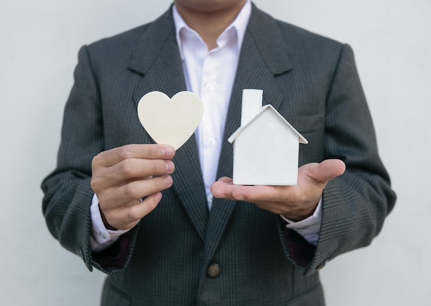 Makelaar in onroerend goed met huismodel en witte breuk