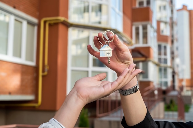 Makelaar overhandigt huissleutel voor de nieuwe eigenaar op huis. verkoop of huur huis