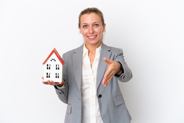 Makelaar vrouw met een speelgoed huis geïsoleerd op een witte achtergrond handen schudden voor het sluiten van een goede deal
