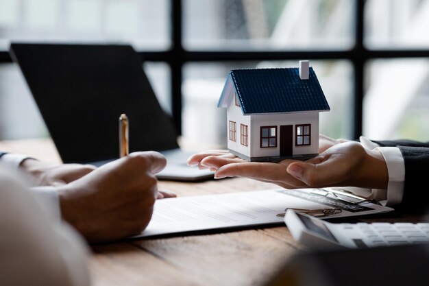 Makelaars hebben een huisvestingsmodel van het project bij zich dat als thuisbezorging aan klanten moet worden doorgestuurd Ideeën voor het verhandelen van onroerend goed en bankleningen voor het kopen en verkopen van huizen en grond