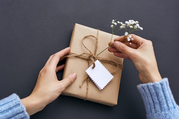 Maken met soulvrouwelijke handen die een mooie geschenkdoos vasthouden en decoreren met wilde bloemen