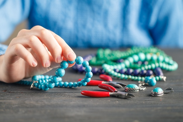 Maken van handgemaakte sieraden. Doos met kralen en glazen hartjes op oude houten oppervlak. Handgemaakte accessoires