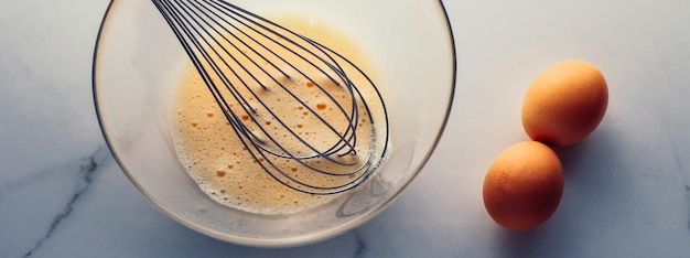 Maken van het mengen van eieren in een kom op marmeren tafel als zelfgemaakt eten plat bovenaanzicht voedselmerk fotografie flatlay en recept voor het koken van blogmenu of kookboekontwerp