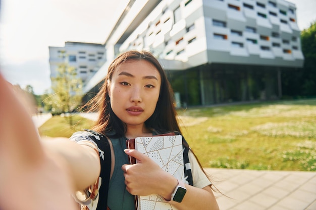 Makes selfie Young asian woman is outdoors at daytime