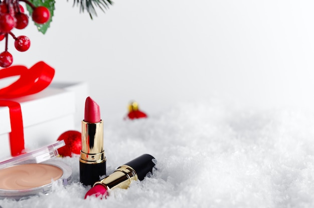 Makeup accessories, cosmetic products on snow background.