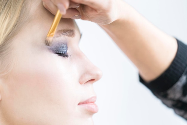 Makeup artist applies glowing eyeshadow Closeup