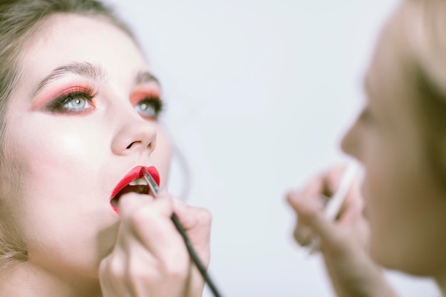 Makeup artist applies red lipstick Beautiful female face Sensual lips