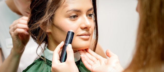 Makeup artist applying cream blush stick foundation on cheek