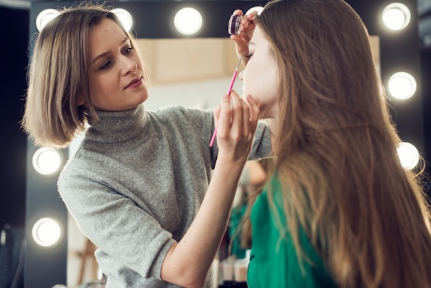 Makeup artist applying eyeliner on model