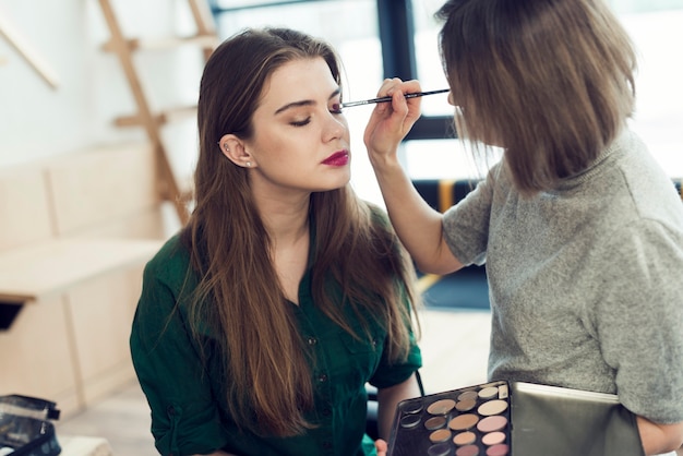 Makeup artist applying eyeshadow on model