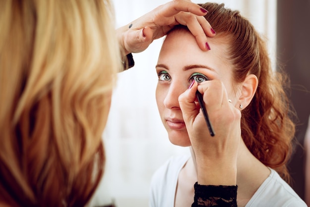 Makeup artist applying the eyeshadow to model.