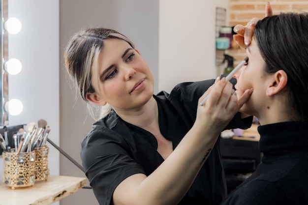 Photo makeup artist applying makeup to a woman