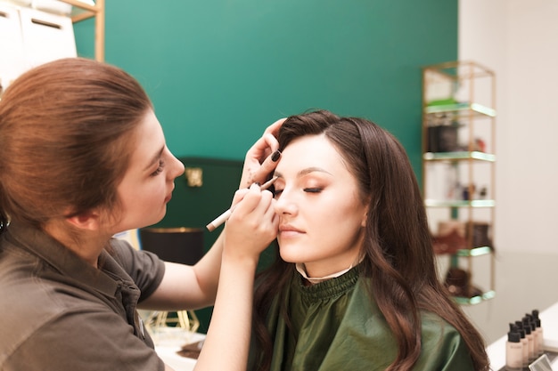 Makeup artist does eyebrow makeup for his client. Eyebrow drawing procedure