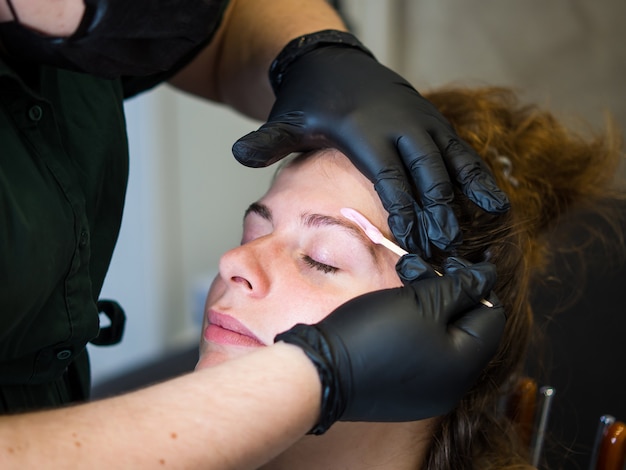 Photo makeup artist does facial hair removal procedure melted wax for facial hair removal.