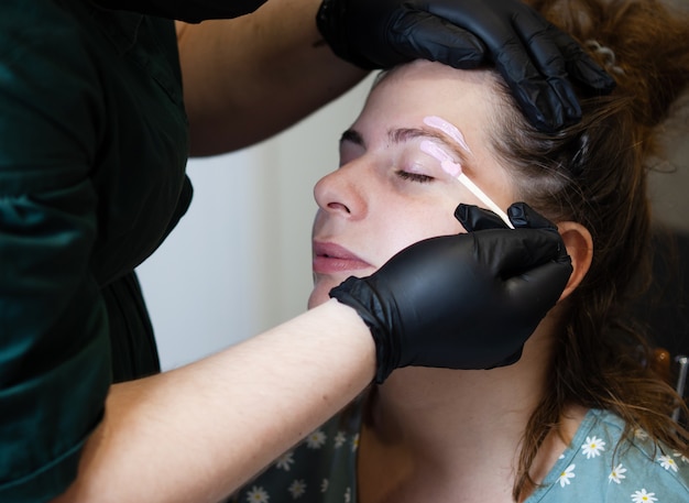 Makeup artist does facial hair removal procedure Melted wax for facial hair removal.