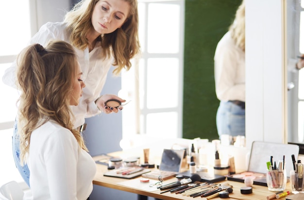 Makeup artist doing make up for young beautiful bride applying wedding makeup